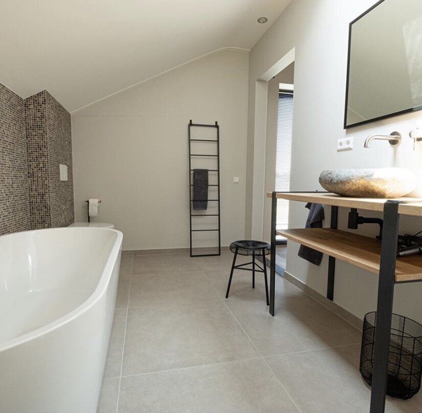 Badkamer met vrijstaand bad en een naadloos afgewerkte douchewand